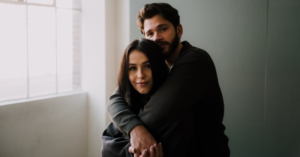 man in black sweater hugging woman in black long sleeve shirt
